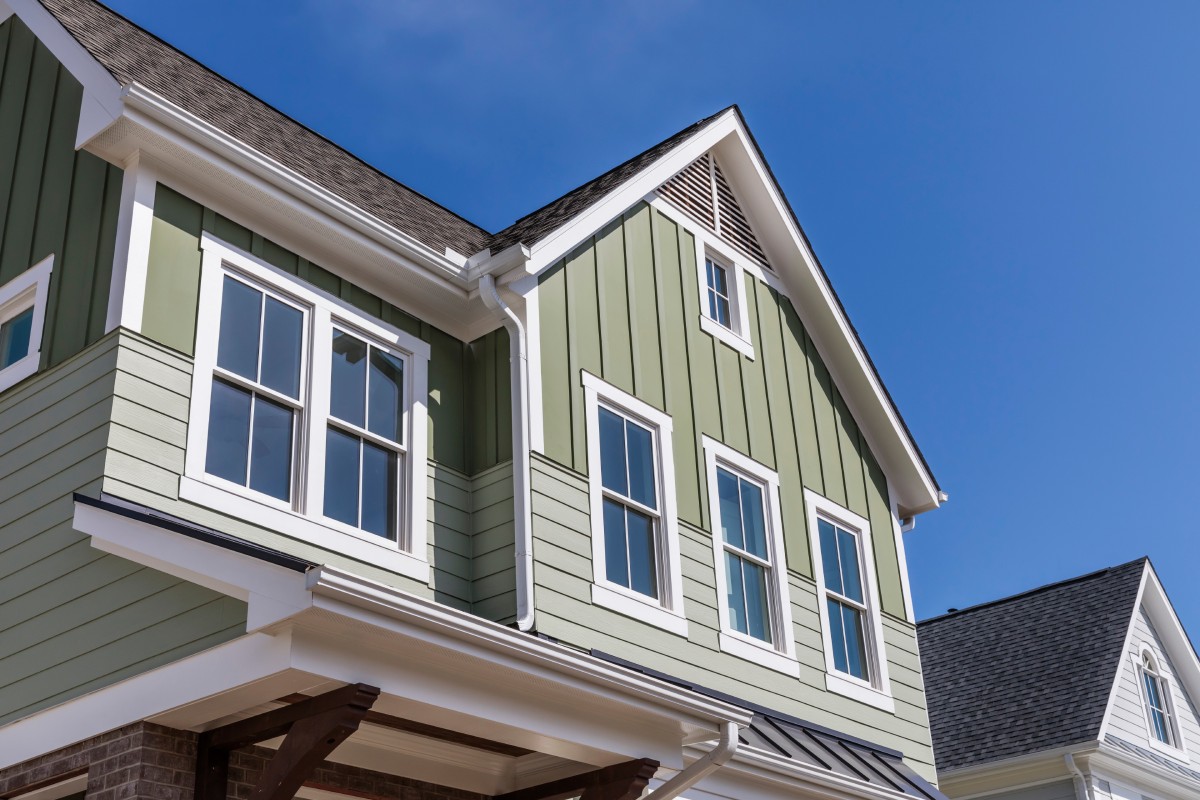 A residential home with vibrant green siding and crisp white trim, highlighting its attractive architectural design.